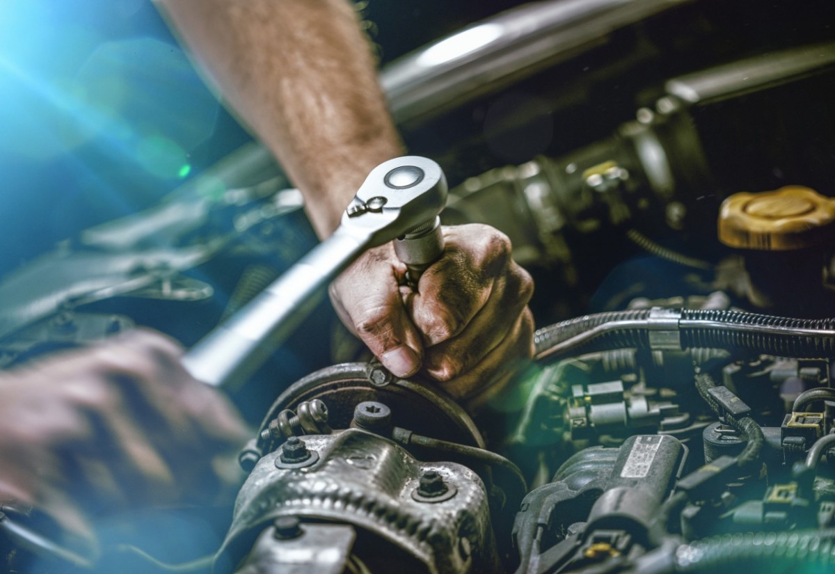 hands turning a wrench on a car